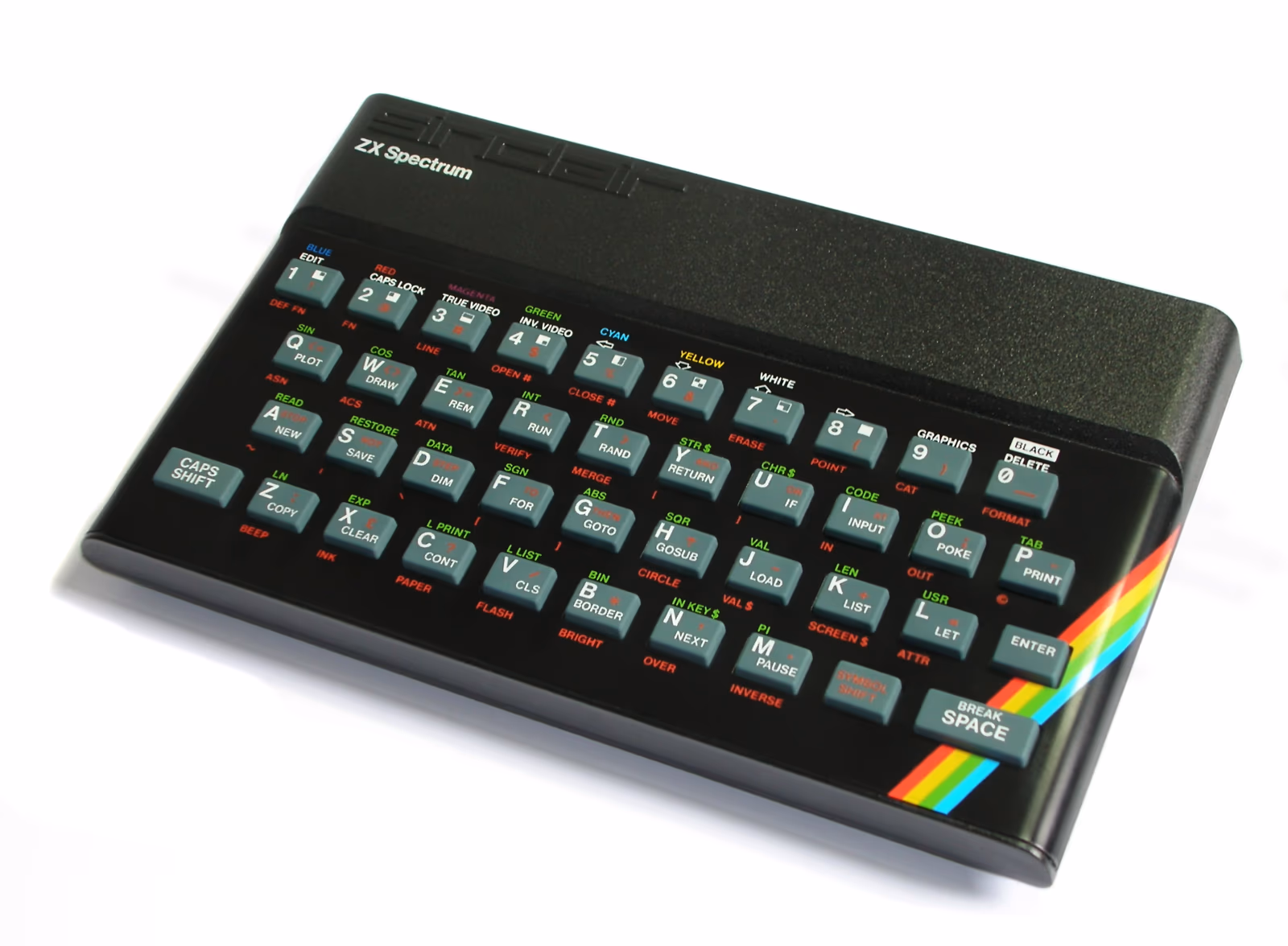 A Sinclair ZX Spectrum 48K seen from three-quarters on a white ground: a black wedge case with a grey rubber keyboard, each key carrying its BASIC keyword in red, green and white, and the rainbow stripe cutting across the lower-right corner.